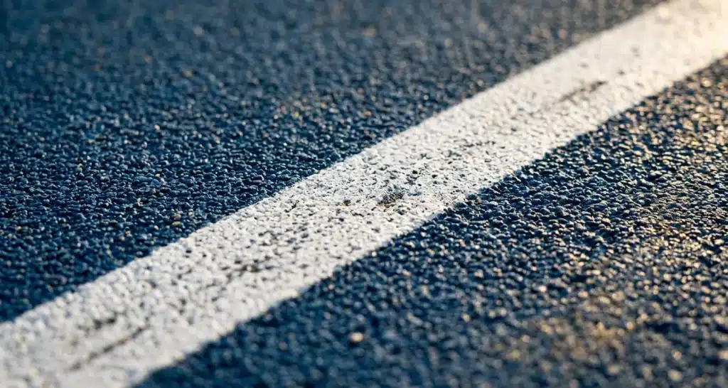 Close-up of Laykold court surface with painted line on an outdoor basketball court